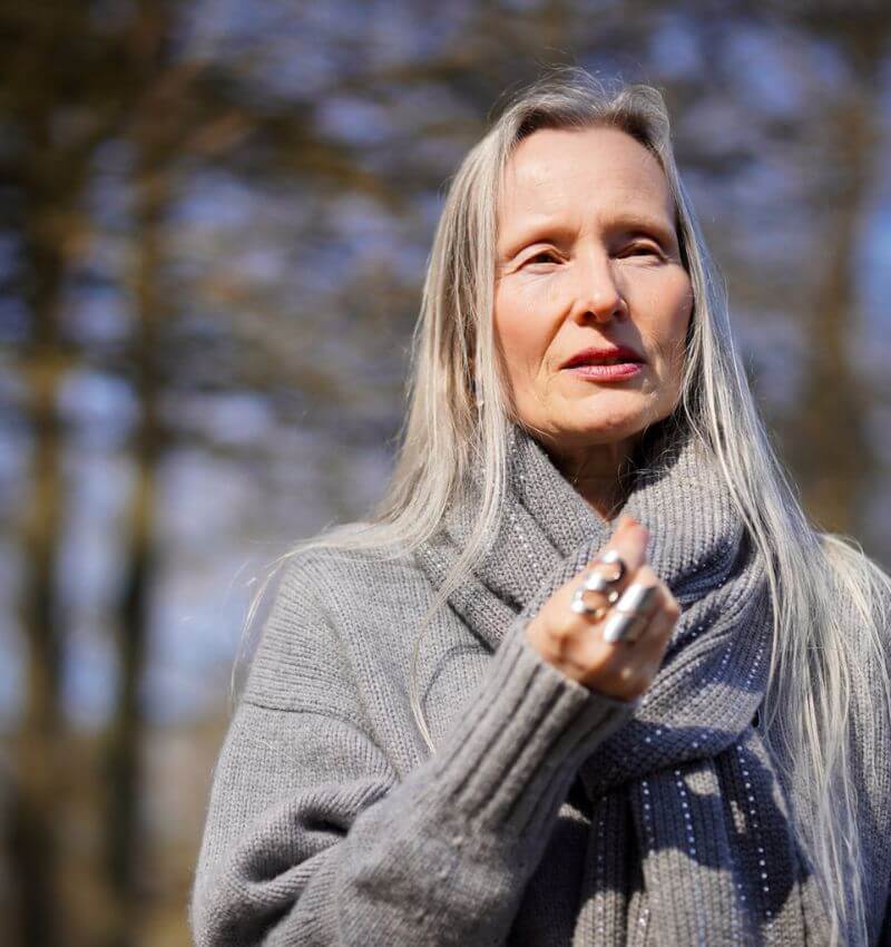 Sabine Weiskopf spricht im Wald stehend, die Sonnenstrahlen berühren ihr Gesicht